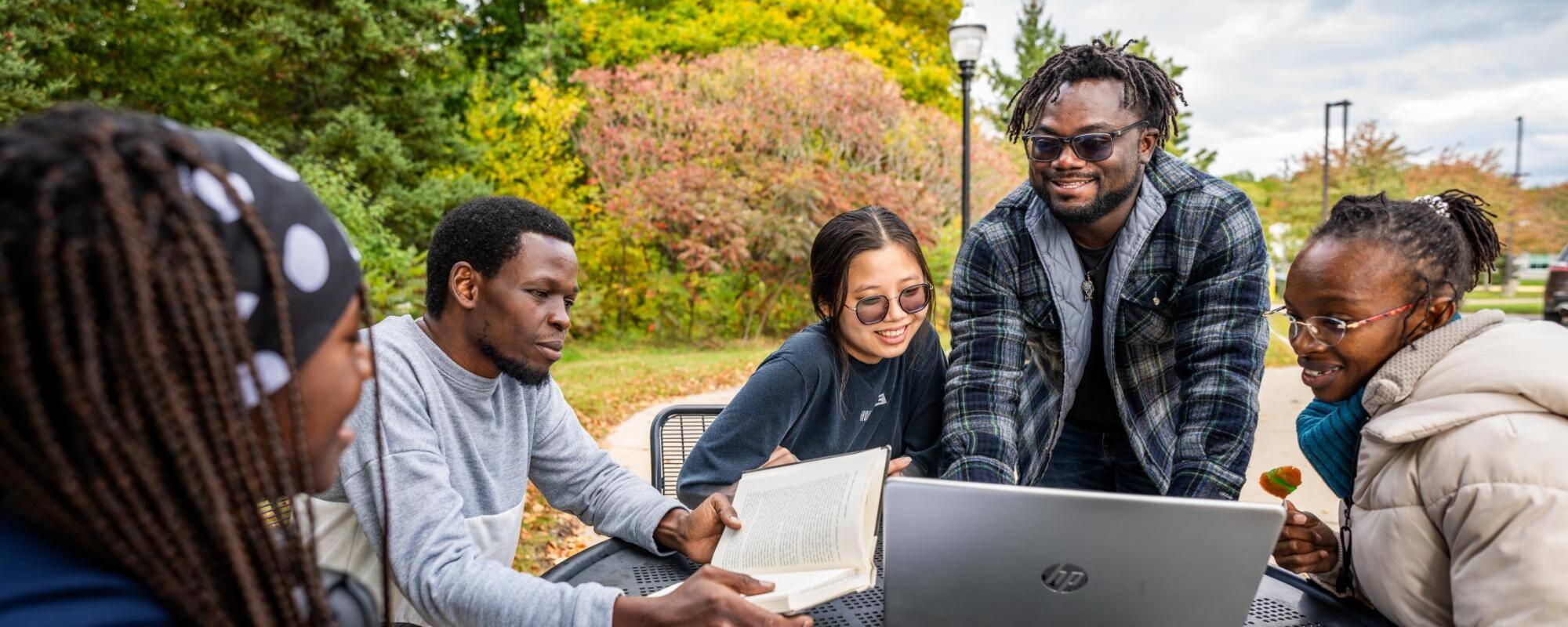 International students gather around a table outside laughing